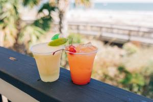 dos bebidas están sentadas en una mesa de madera en Sandcastle Oceanfront Resort at the Pavilion, en Myrtle Beach