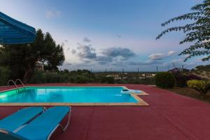 una gran piscina con 2 sillas azules. en Maroulas Villa Estate en Maroulás