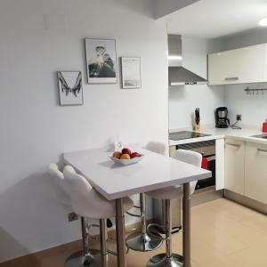a white kitchen with a white table and chairs at Apartamento con vistas al mar in Alicante