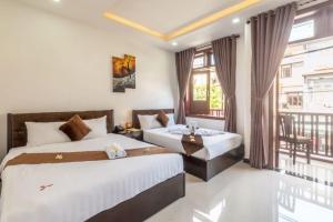 um quarto de hotel com duas camas e uma varanda em Miss Ten Homestay em Hoi An