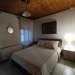 sypialnia z białym łóżkiem i drewnianym sufitem w obiekcie VILLA KATERINA w mieście Tríkala