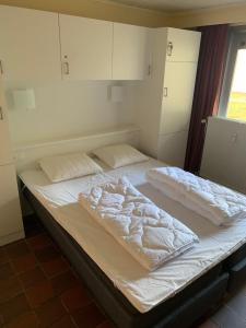 a bed with white sheets on it in a room at Hengelhoef Acacia 3 in Drijhoeven