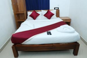 a bed with red and white sheets and red pillows at Airport Cochin Grand Residency , NEDUMBASSERY in Angamali
