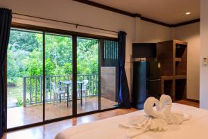 a bedroom with a bed and a balcony with a table at Bang Po Garden in Ban Bang Po