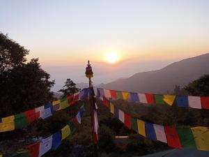 un coucher de soleil avec drapeaux de prière sur une colline dans l'établissement Dubochaur Rest house & homestay, à Nagarkot