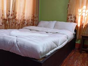 an unmade bed in a room with a window at Dubochaur Rest house & homestay in Nagarkot