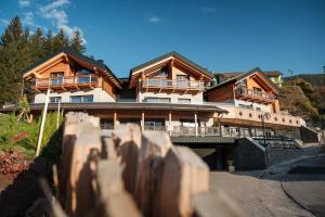 una gran casa de madera con una valla delante de ella en La Dila Dolomiti Mountain Lodge, en Andalo