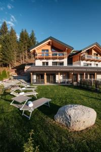 a house with a yard with lounge chairs at La Dila Dolomiti Mountain Lodge in Andalo