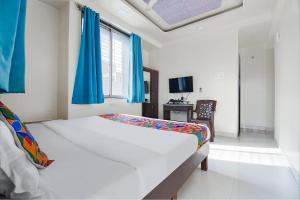 浦那FabExpress Galaxy Apartments - Lohegaon chowk的卧室里有一张带蓝色窗帘的大床