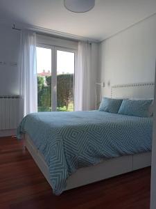 a bedroom with a bed and a large window at Bajo con jardín privado in Santander