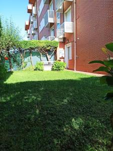 a green yard next to a brick building at Bajo con jardín privado in Santander