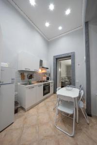 uma cozinha com electrodomésticos brancos e uma mesa e cadeiras em Cattedrale Duomo 77 Apartments By Dimorra em Nápoles