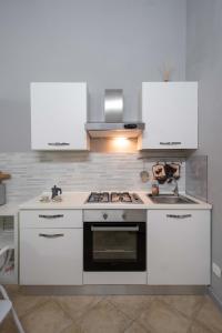 uma cozinha com armários brancos e um forno com placa de fogão em Cattedrale Duomo 77 Apartments By Dimorra em Nápoles