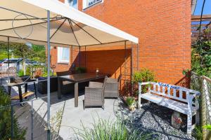 een patio met een tafel en een parasol bij Ferienwohnungen Wind & Meer in Neuharlingersiel