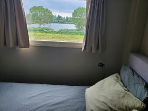 een slaapkamer met een bed en een raam met uitzicht bij Vakantiehuis Meerzicht in Nederhemert