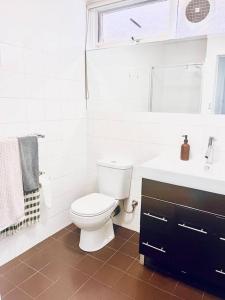 La salle de bains blanche est pourvue de toilettes et d'un lavabo. dans l'établissement Two bedroom South Melbourne Apartment on Montague, à Melbourne