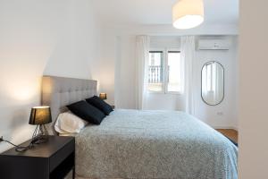 1 dormitorio con 1 cama con edredón azul y ventana en LUANDCIA Soho 3, en Málaga