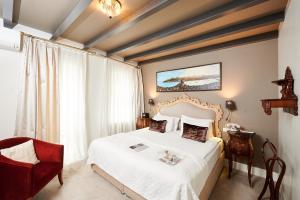 ein Schlafzimmer mit einem weißen Bett und einem roten Stuhl in der Unterkunft Faik Pasha Hotels Special Category Beyoglu Istanbul in Istanbul