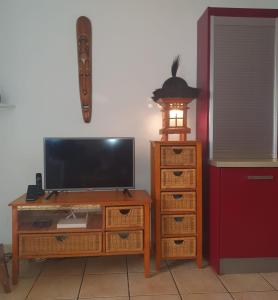 einen TV und einen Schreibtisch mit einem TV und einer Kommode in der Unterkunft Les Sternes 2 - Apt T2 pieds dans l'eau et jardin in Trois Bassins