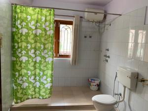 a bathroom with a toilet and a green shower curtain at Krimson Bricks Homestay in Varanasi
