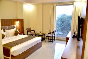 a hotel room with a bed and a large window at Hotel Aarna in Jaipur