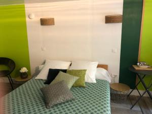 een groene en witte slaapkamer met een bed met kussens bij Le jardin de félicie in Trévoux