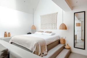 een witte slaapkamer met een bed en een spiegel bij Suite-Suite luxury private guesthouse in Zandvoort