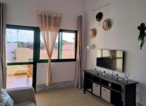 a living room with a television and a window at Mirador de Sotavento Apartment 8206 in Costa Calma
