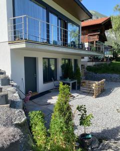 een huis met een balkon en een bank in een tuin bij Hotel Schwarzer Adler in Pettneu am Arlberg