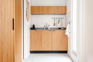 a kitchen with wooden cabinets and a sink at Suite-Suite luxury private guesthouse in Zandvoort