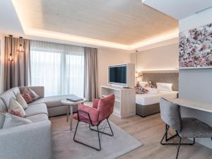 ein Wohnzimmer mit einem Sofa, einem TV und einem Bett in der Unterkunft Aktiv Hotel Schweizerhof Kitzbühel in Kitzbühel