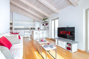 a living room with a white couch and a tv at La Tessella - Suite Centrale con Posto Auto Gratis in Alba