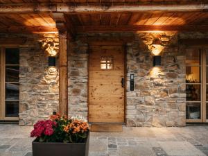 eine Eingangstür eines Steinhauses mit Blumen davor in der Unterkunft Die Suttenhütte in Rottach-Egern