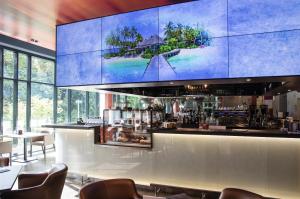 a bar in a restaurant with a large screen at aja Bad Saarow in Bad Saarow