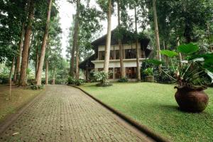 uma casa no meio de um jardim com uma estrada de tijolos em Villa Puncak by Plataran em Puncak