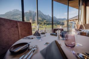 a table with utensils on it with a view of mountains at Hotel Riederalm in Leogang