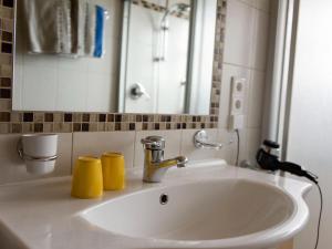 a bathroom sink with two yellow cups on it at Apartments home Niedermunthof, Villnöß in Funes