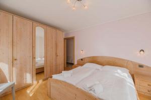 1 dormitorio con cama de madera y espejo en Appartamenti Cèsa Sorèie Dolomiti, en Canazei