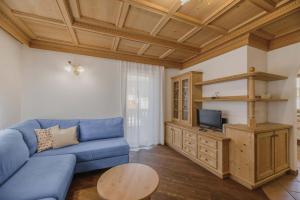 salon z niebieską kanapą i telewizorem w obiekcie Appartamenti Cèsa Sorèie Dolomiti w mieście Canazei