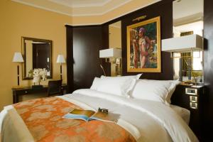 Royal Hotel Oran - MGallery Hotel Collection في وهران: غرفة نوم بسرير مع كتب ولوحة