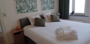 een slaapkamer met een bed met een witte deken erop bij De Galerie - green leaves in Ieper