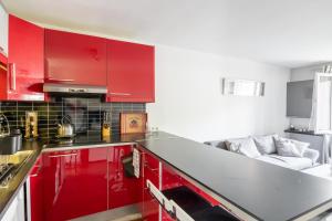 kuchnia z czerwonymi szafkami i kanapą w obiekcie Maison Mareuil w mieście Mareuil-lès-Meaux +4 zdjęcia
