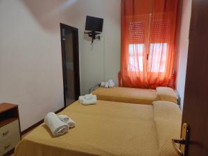 2 łóżka w pokoju z pomarańczowymi zasłonami w obiekcie Lanterna Verde w mieście Torre Orsaia
