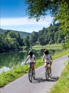 two people riding bikes down a road next to a river at Le Cocon Rethelois. in Rethel