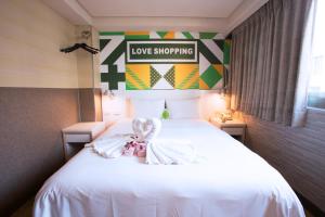a bedroom with a white bed with a love shopping sign on it at Ximen Citizen Hotel in Taipei