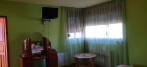 a green room with a television and a table and a window at Hotel Ambrozia in Kotel