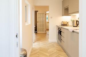 cocina con armarios blancos y suelo de madera en Bright & Airy 2BD - 10 mins walk to Chelt Centre! en Cheltenham
