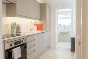 una cocina con armarios blancos y fregadero en Bright & Airy 2BD - 10 mins walk to Chelt Centre! en Cheltenham