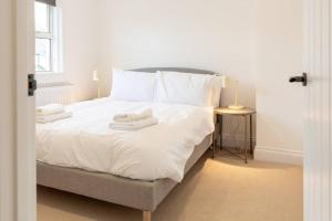 Una cama blanca con dos toallas encima. en Bright & Airy 2BD - 10 mins walk to Chelt Centre! en Cheltenham