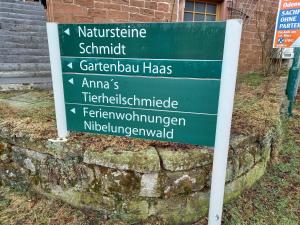 a green sign in front of a brick building at Appartement Spatzennest in Mossautal
